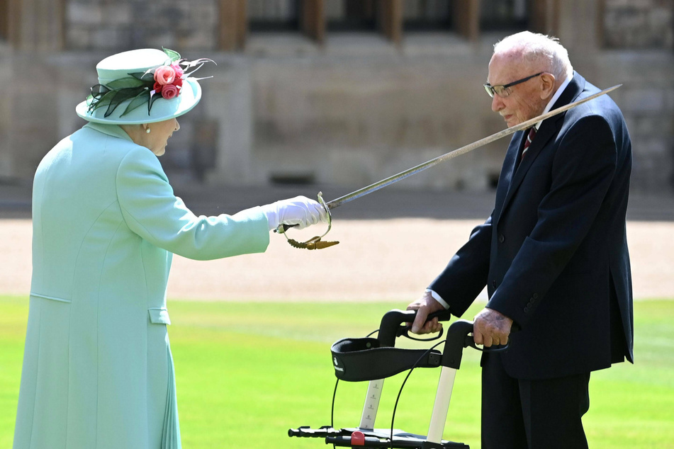 Queen Elizabeth II knights Captain Sir Tom Moore at an Investiture at Windsor Castle, United Kingdom.
