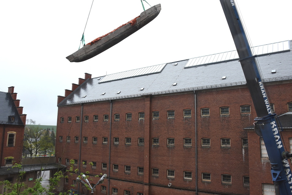 Kommt ein Kanu geflogen: Ein Kran hievte das altertümliche Wasserfahrzeug zum Dach des früheren Stollberger Frauengefängnisses.