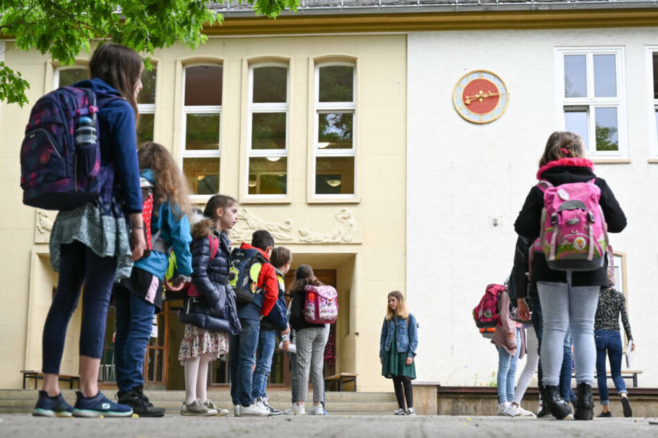 Schülerinnen und Schüler der vierten Klasse der Robert-Schumann-Grundschule stehen vor dem Unterricht mit Abstand zueinander auf dem Schulhof.