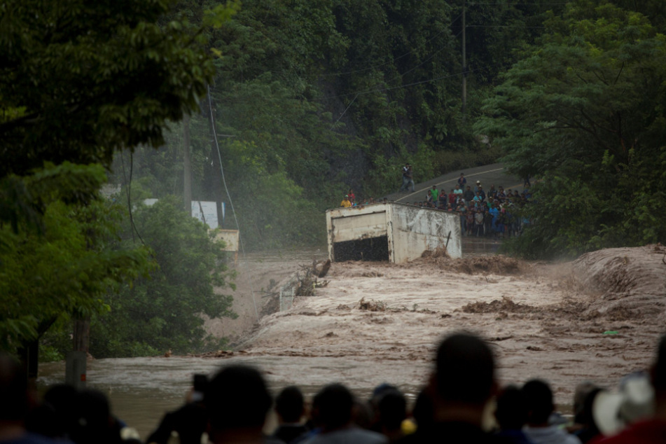 Guatemala, Camotan: Dorfbewohner schauen zu, wie ein Lkw vom Strom des Rio-Grande-Flusses nach dem Durchzug von "Iota" gezogen wird.