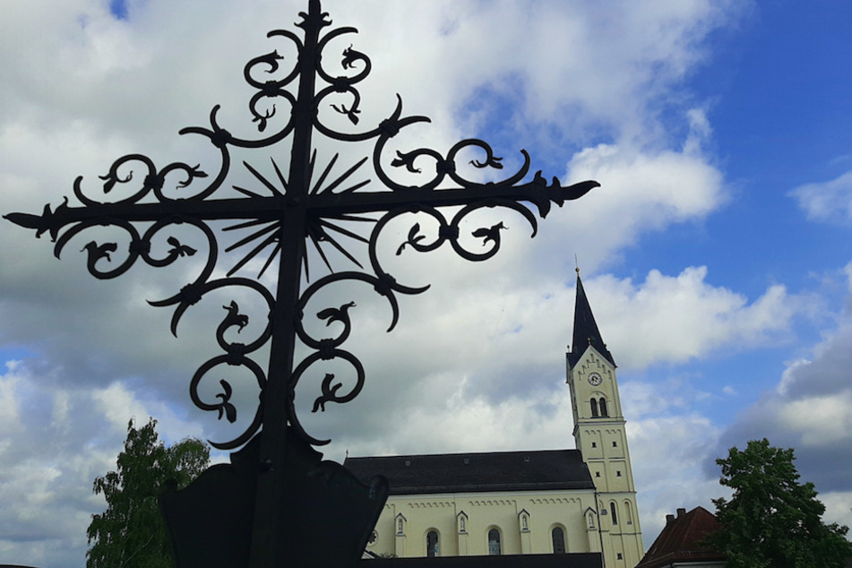 Ein Kreuz steht vor der Kirche St. Nikolaus in Garching an der Alz. Dort war ein wegen sexuellen Missbrauchs verurteilter katholischer Priester rund 20 Jahre lang als Pfarrer tätig.