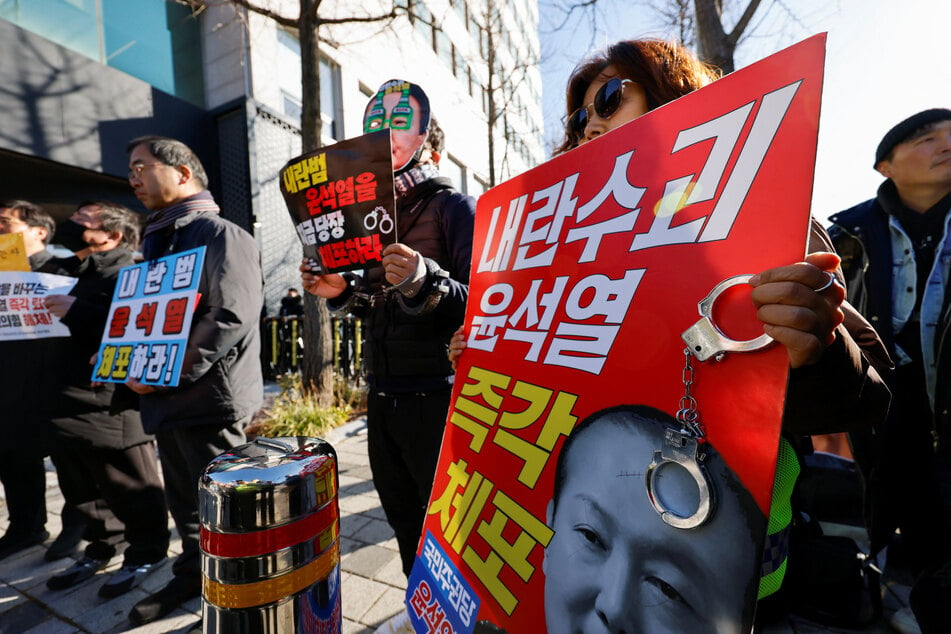 Protesters celebrate a South Korean court's decision to issue an arrest warrant for suspended president Yoon Suk Yeol over his brief declaration of martial law.