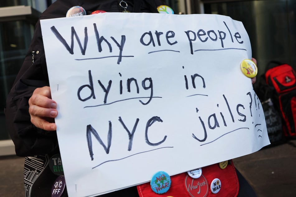 A person holds a sign reading "Why are people dying in NYC jails?" during a rally outside Governor Kathy Hochul's office in Manhattan.
