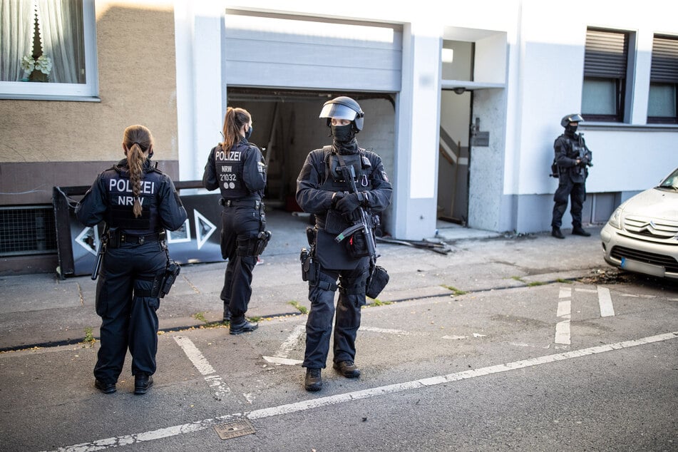 Wuppertal: Polizeibeamte stehen vor einem Wohnhaus. Bei einer Razzia gegen Clankriminalität sind in Nordrhein-Westfalen am frühen Morgen mehrere Wohnungen und Firmen durchsucht worden.