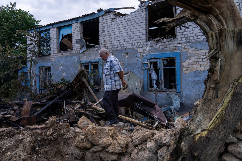 Ein Einheimischer geht vor einem durch russischen Beschuss beschädigten Gebäude entlang. In der südukrainischen Stadt Cherson kommt es immer wieder zu Toten und Verletzten infolge des Krieges.