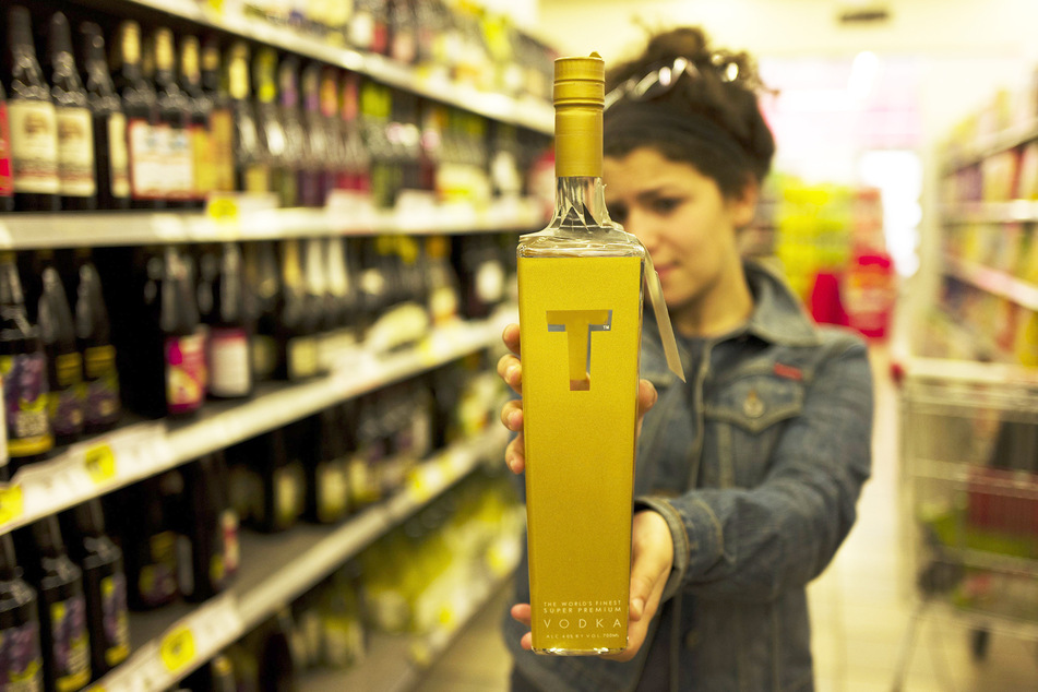 Eine Frau hält eine Flasche Vodka in einem Supermarkt.
