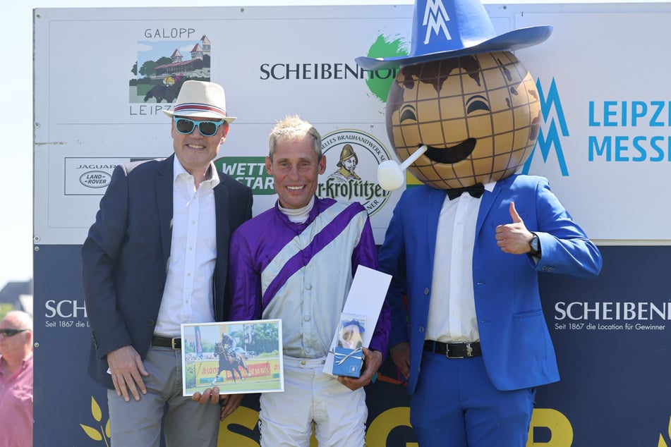 Jockey Alexander Pietsch belegte zusammen mit Pferd Nutrias den ersten Platz bei dem Rennen "Preis der Leipziger Messe". Natürlich gratulierte das Messemännchen (r.) gleich mit.