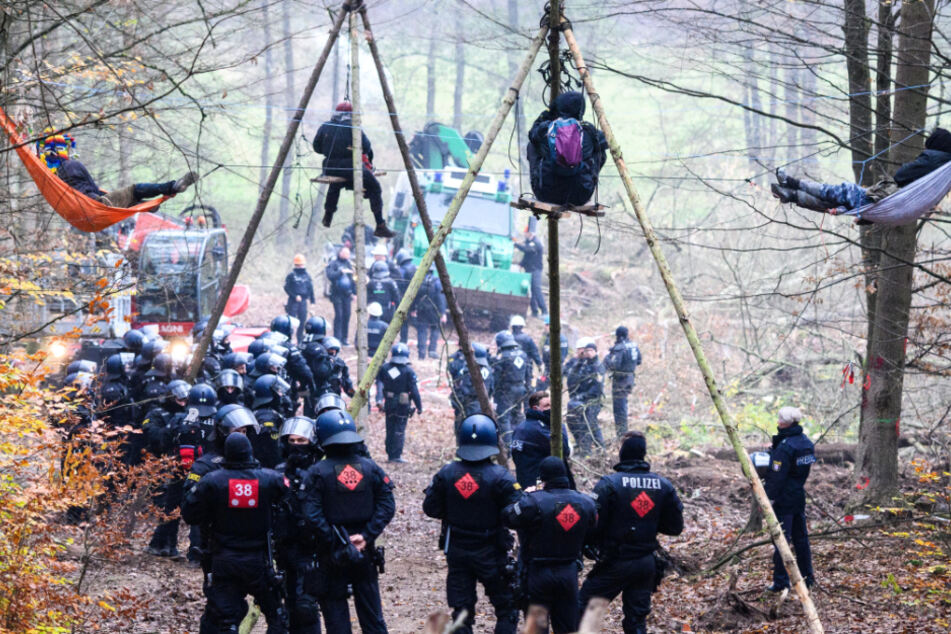 Einsatzkräfte der Polizei stehen bei Baumbesetzern im Dannenröder Forst, die in Tripods und Hängematten verharren.