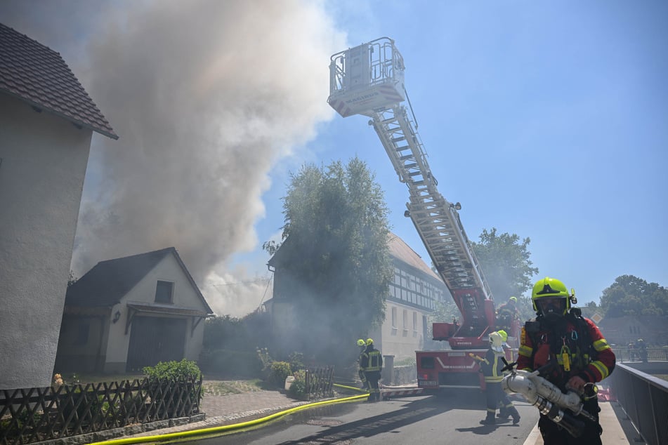 Große Rauchwolken steigen den Himmel empor, während die Feuerwehrleute im Einsatz sind.