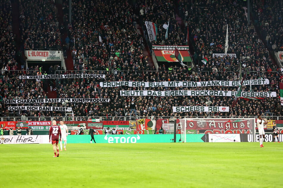 "Dein Charakter passt zum Kunstprodukt" steht auf Bannern im Augsburger Stadion.