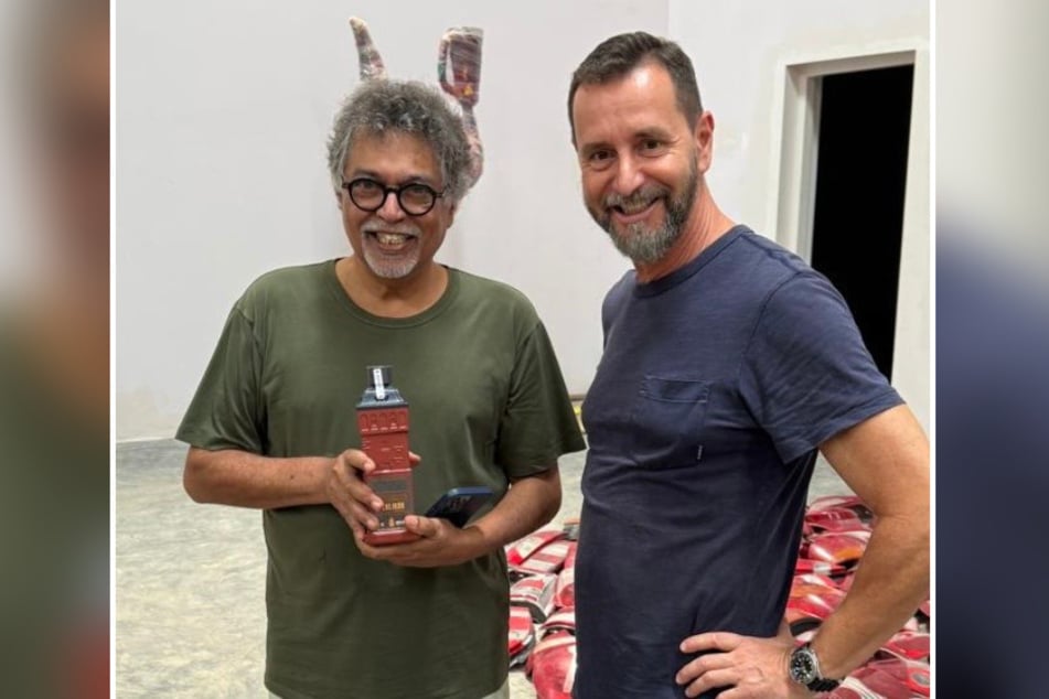 Künstler Subodh Kerkar (66, l.) nimmt die "Roter Turm"-Schnapsflasche von André Donath (59) in Empfang.