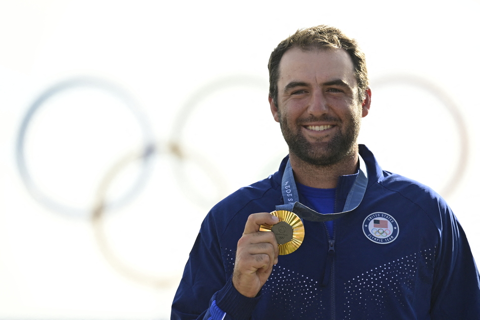 Gold medallist US' Scottie Scheffler poses for pictures on the podium after round 4 of the men’s golf individual stroke play of the Paris 2024 Olympic Games at Le Golf National in Guyancourt, south-west of Paris on Sunday.