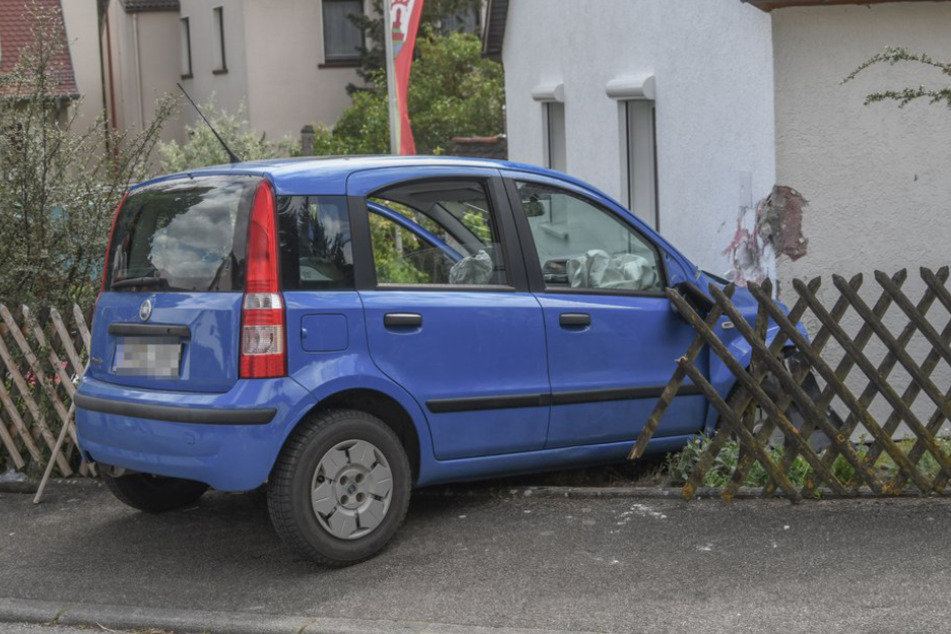 Das Auto durchbrach einen Zaun und kam an einer Hauswand zum Stehen.