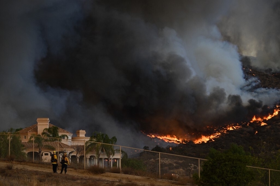 Plumes of smoke rise as wildfire approaches a home during the Fairview Fire near Hemet, California, in Riverside County on September 7, 2022.