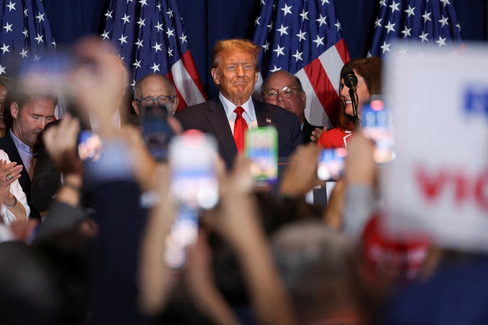 Former president and 2024 frontrunner Donald Trump stands on stage as he hosts a South Carolina Republican presidential primary election night party in Columbia.
