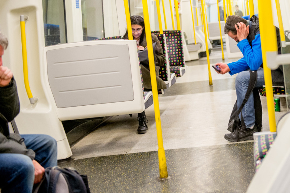 Ein Mann (l.) hustet in einem fast leeren Londoner U-Bahnwagen. (Symbolbild)