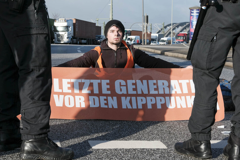 So weit kam es nicht: Ein Aktivist blockiert in Hamburg am Dienstag eine Straße. Am Mittwoch war die Polizei schneller.