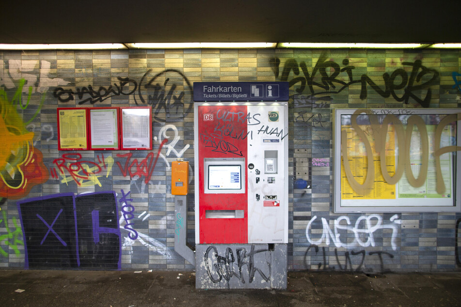 Ein Fahrkartenautomat und Fahrpläne am DB-Haltepunkt Köln Geldernstraße/Parkgürtel sind mit Graffiti-Schmierereien verunstaltet.