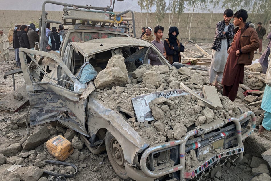 Afghanische Anwohner neben einem beschädigten Auto am Ort eines grenzüberschreitenden Angriffs in der Provinz Nangarhar.