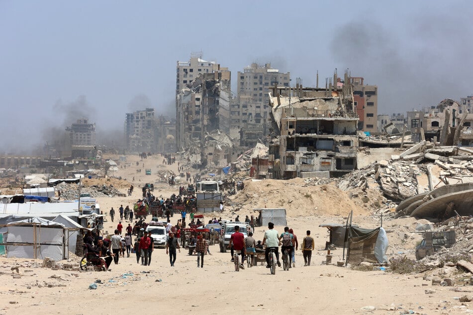 Palestinians transport their belongings as they flee the northern Gaza Strip toward the south along the coastal al-Rashid road on May 25, 2025.