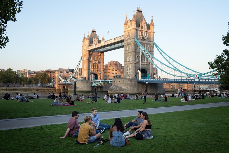 London: Sechs Personen sitzen auf dem Rasen des Potters Fields Park vor der Tower Bridge. Um einen starken Anstieg der Coronavirus-Fälle zu verhindern, traten in Großbritannien neue Beschränkungen für die Zusammenkunft von Personen in Kraft.