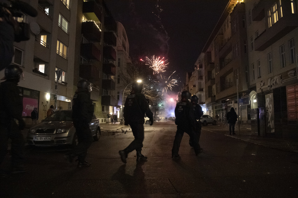 Behelmte Polizisten überqueren eine Straße zum Jahreswechsel in Berlin.