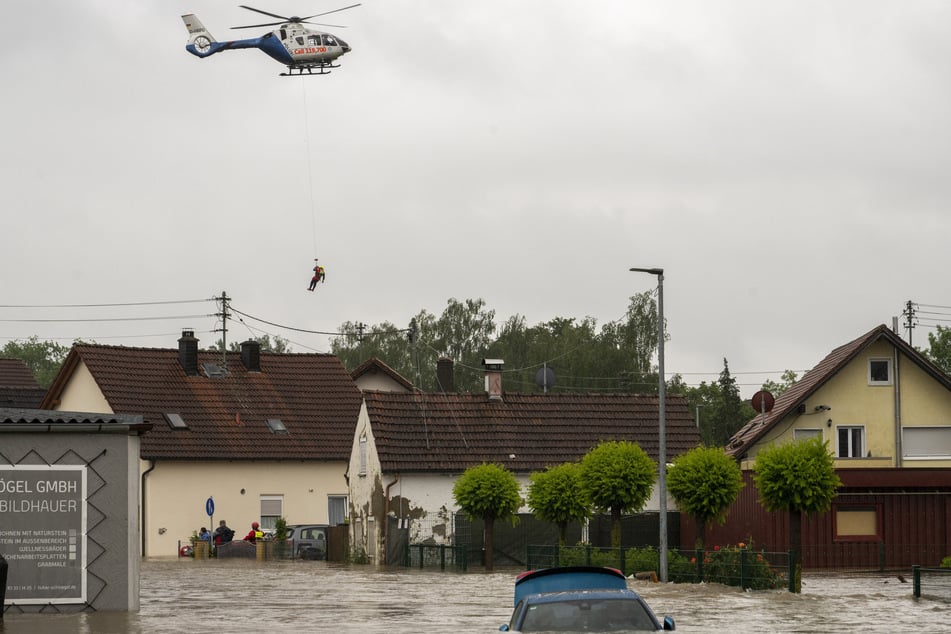 Wasserretter seilten sich aus einem Polizeihubschrauber ab, um Bewohner aus ihren Häusern retten zu können.