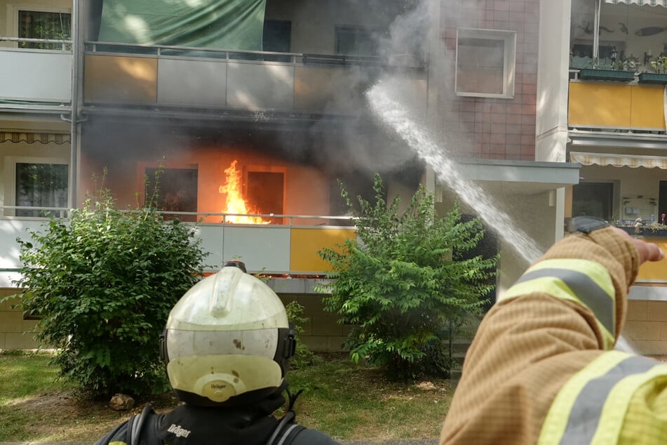 Wohnungsbrand in Dresden-Gorbitz: Feuerwehrleute bekämpften die Flammen mittels Strahlrohren von der Wiese aus.