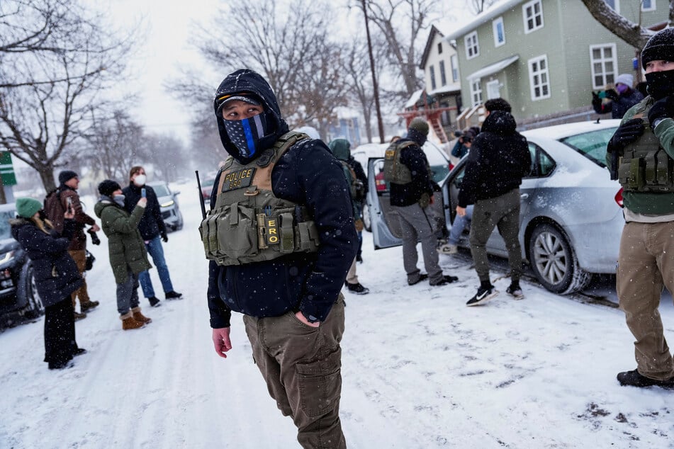 A member of ICE's Enforcement and Removal Operations stands guard while a man is detained by agents during a raid in Minneapolis, Minnesota, on January 18, 2026.