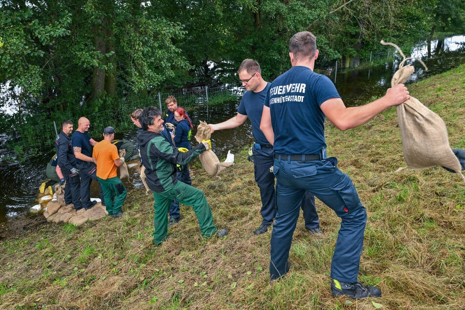 Die Freiwillige Feuerwehr dichtet eine Sickerstelle an einem Deich ab.