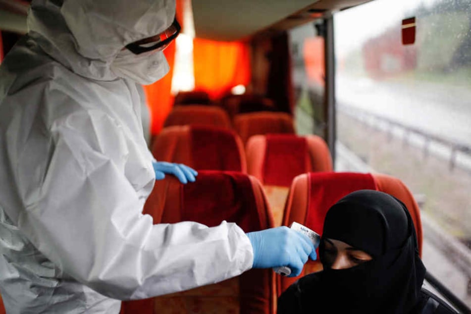 Istanbul: Ein medizinischer Mitarbeiter im Schutzanzug misst in einem Bus die Körpertemperatur einer Frau.