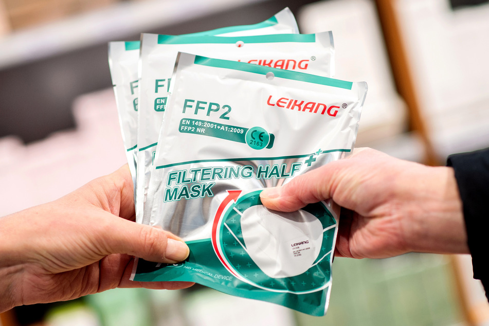 Eine Apothekerin gibt einer älteren Kundin mehrere FFP2-Atemschutzmasken.