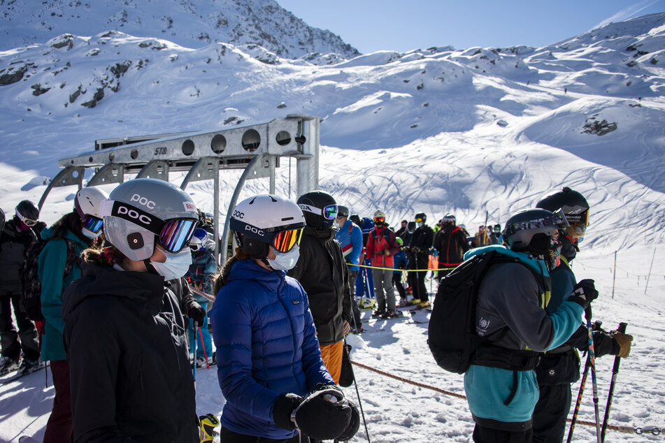 Skifahrer mit Gesichtsmasken stehen am Eröffnungstag des Skigebiets Verbier in den Schweizer Alpen in einer Schlange für den Sessellift an.