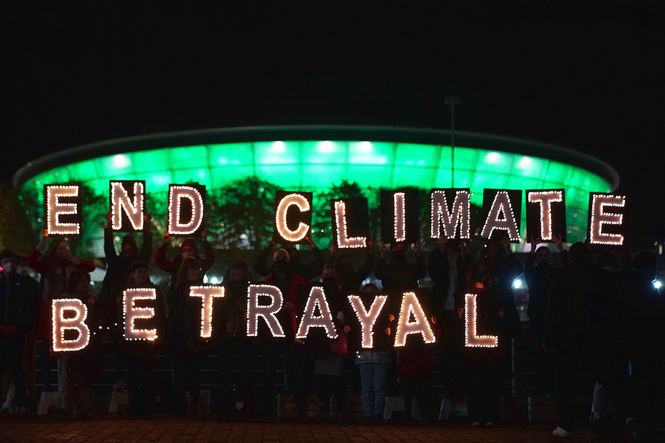 Climate activists hold giant illuminated letters spelling out End Climate Betrayal during a protest during COP26 in Glasgow.