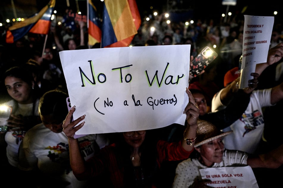 A supporter of Venezuela's President Nicolas Maduro holds a sign reading "No to War" during a rally demanding peace in Caracas on December 15, 2025.