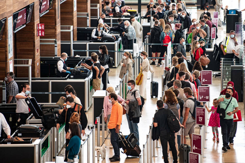 Reisende stehen am Flughafen BER am Security Check. Ein Grund für die stark ansteigende Inzidenz in Berlin könnte die Reisewelle während der Ferienzeit sein.