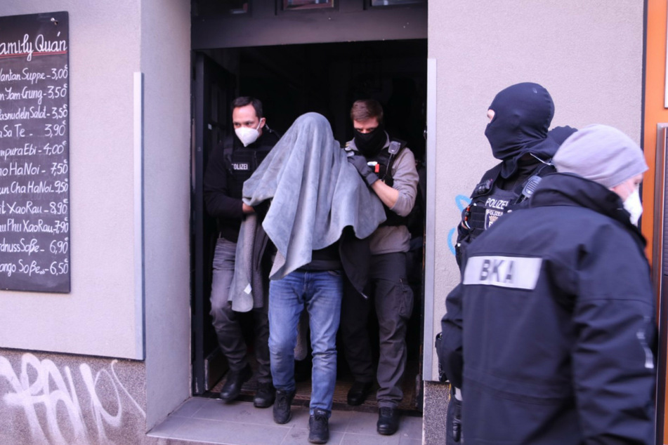 Die Polizei führt einen Mann, mit einer Decke über dem Kopf, in der Wildenbruchstraße in Berlin-Neukölln ab.