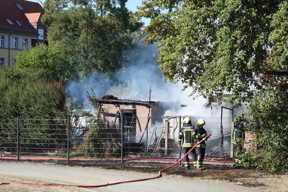 Die Feuerwehr ist mit mehreren Kräften vor Ort und löscht die Lauben.