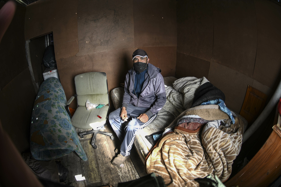 Argentinien, La Plata: Ein Mann mit Mundschutz sitzt inmitten der Corona-Pandemie auf einer Matratze in einer Hütte aus Pappe in einem bestzten Landstück. In der Pandemie soll die Armut im südamerikanischen Land deutlich zugenommen haben.