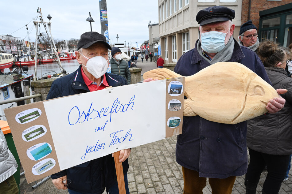 Ein Gegendemonstrant aus Warnemünde hält ein Plakat mit der Aufschrift "Ostseefisch auf jeden Tisch".
