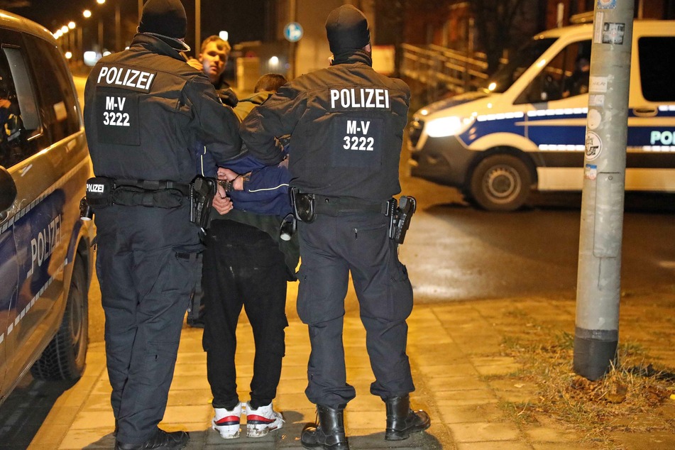 Einer der beiden Verdächtigen wird von der Polizei festgenommen.