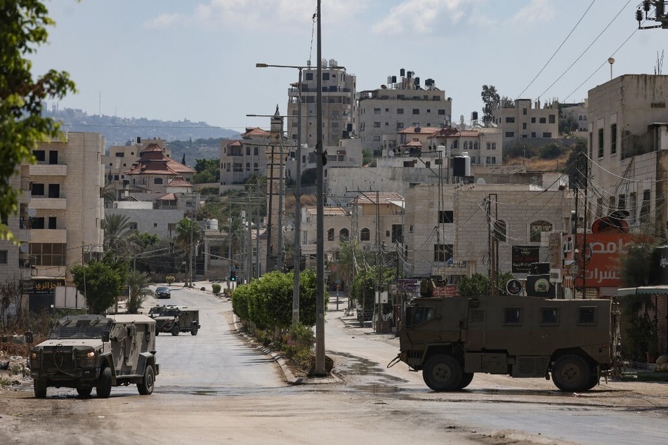 Israeli military vehicles roll down a street in the occupied West Bank city of Tulkarem on August 3, 2024.