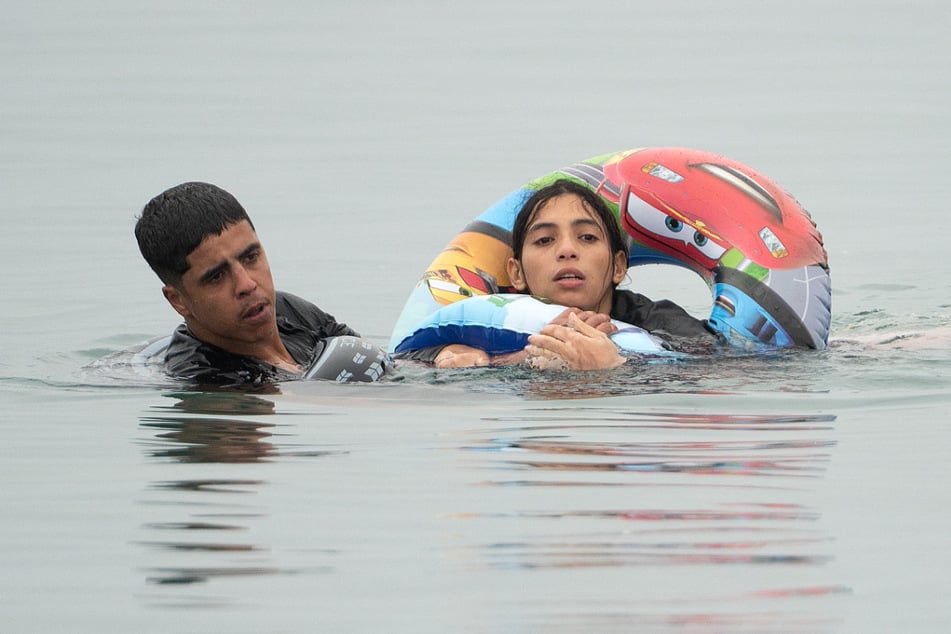 Migranten schwimmen an einer Grenzanlage von Marokko vorbei, um nach Ceuta zu gelangen.