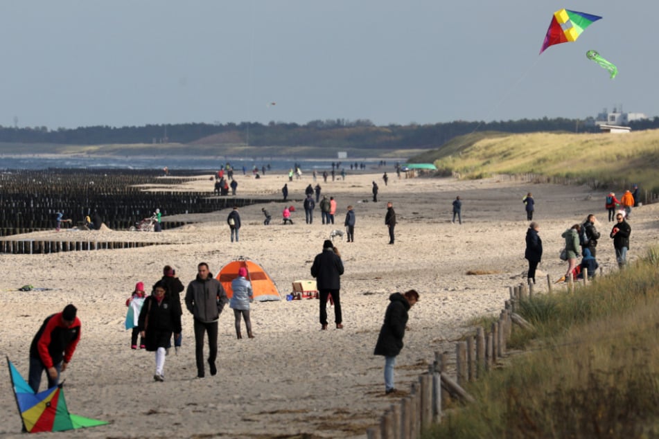 Touristen sind am Ostsee-Strand von Graal-Müritz unterwegs.