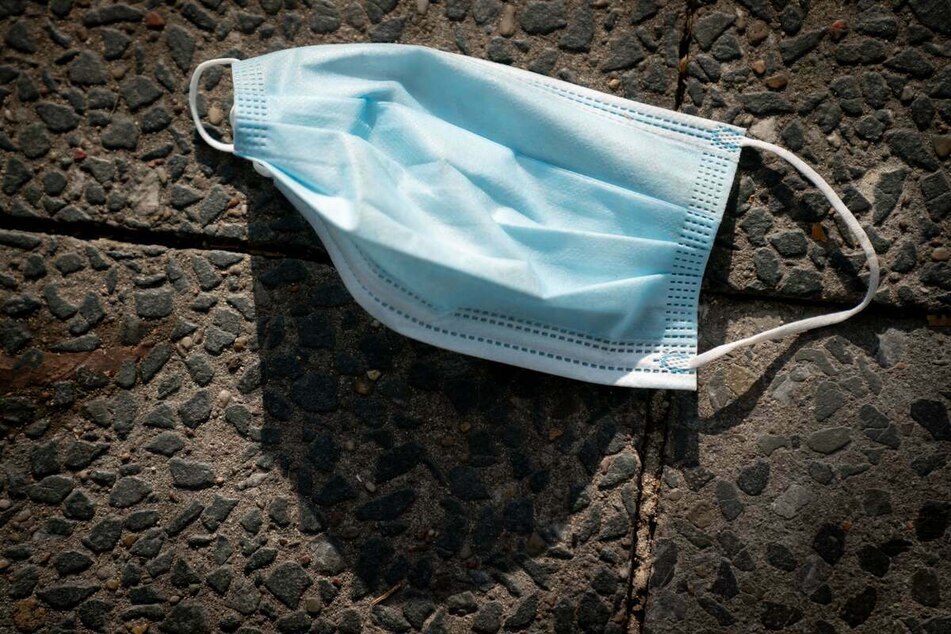 Eine Einwegmaske liegt auf dem Boden. (Symbolbild)