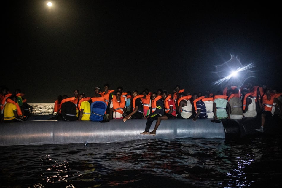 Migranten warten in einem Schlauchboot darauf an Bord des Rettungsschiffes "Louise Michel" aufgenommen zu werden.