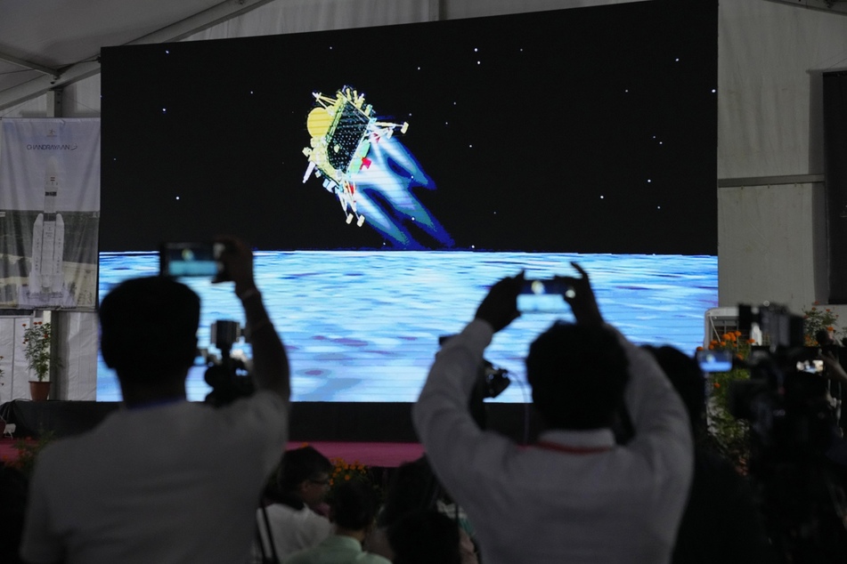 Journalisten filmen die Live-Übertragung der Landung des Raumschiffs "Chandrayaan-3" auf dem Mond in der ISRO-Einrichtung für Telemetrie, Ortung und Kommandonetz.