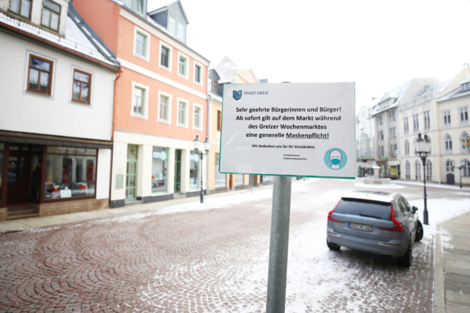 Das Hinweisschild zur Maskenpflicht auf dem leeren Marktplatz im thüringischen Greiz.