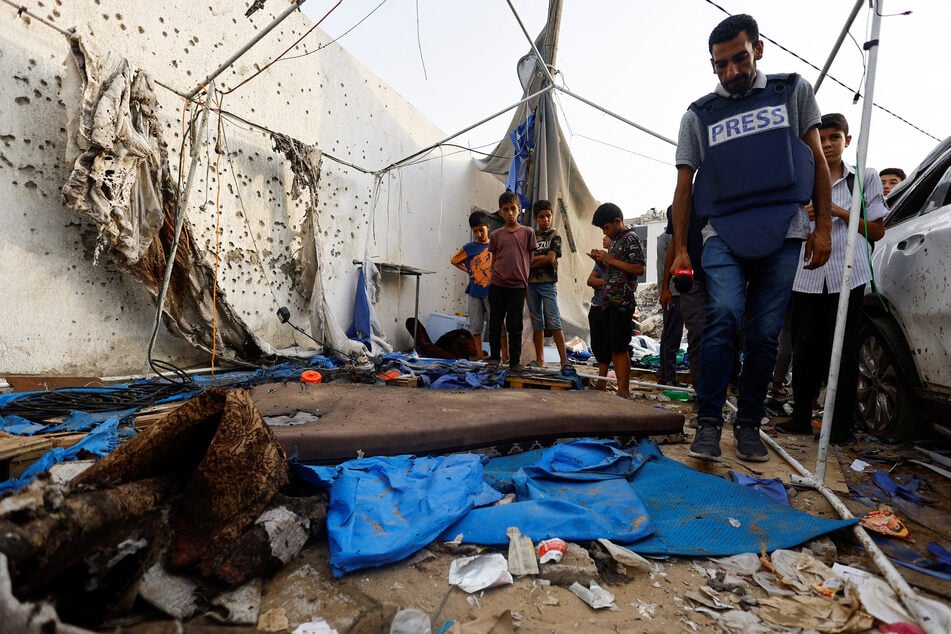 A member of the media inspects the damage at the site of an Israeli strike on a tent near Shifa Hospital where Al Jazeera journalists Anas Al Sharif, Mohammed Qreiqeh, Ibrahim Zaher, and Mohammed Noufal were killed, in Gaza City on August 11, 2025.
