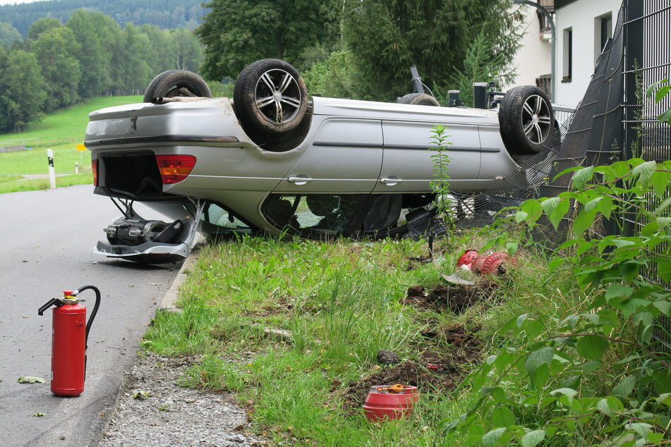 Gartenzaun-Crash im Erzgebirge! Ein BMW-Fahrer landete am Montag mit seinem Wagen auf dem Dach und beschädigte dabei einen Zaun eines Einfamilienhauses.